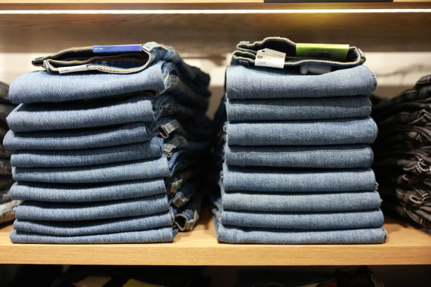 Many jeans in closet. Stack of jeans on shelf. Concept of buy , sell , shopping and jeans fashion .